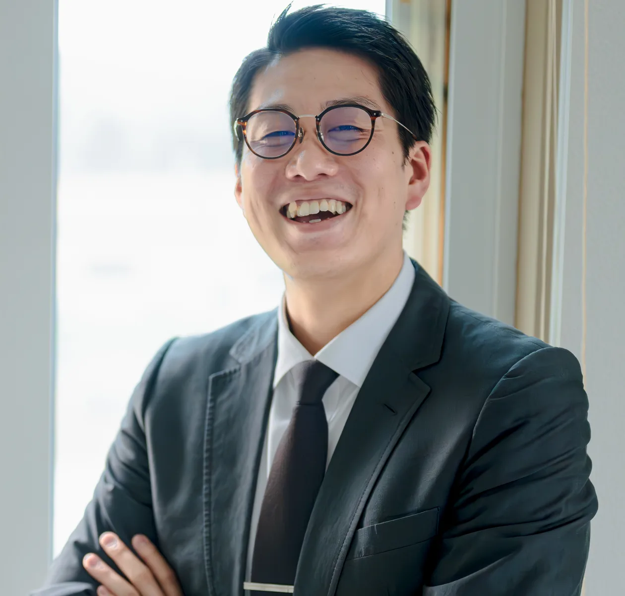 창가에 팔짱을 끼고 서서 웃는 사람